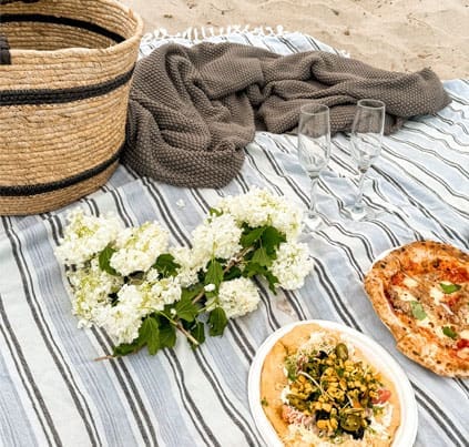 Luxury beach picnic with gourmet food, flowers and champagne glasses in Matakana, New Zealand